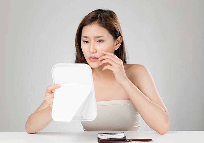 Woman examining skin irritation caused by environmental stressors.