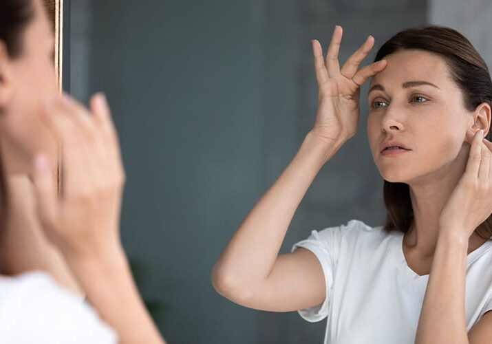 woman looking at her skin in the mirror